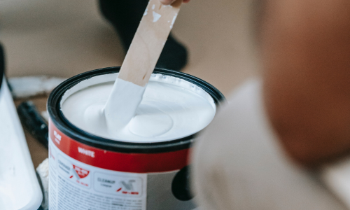 Stirring white paint with paint stick